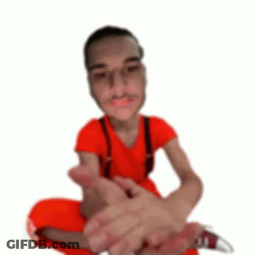 A Man In A Red Shirt And Suspenders Is Sitting On The Floor With His Legs Crossed . GIF