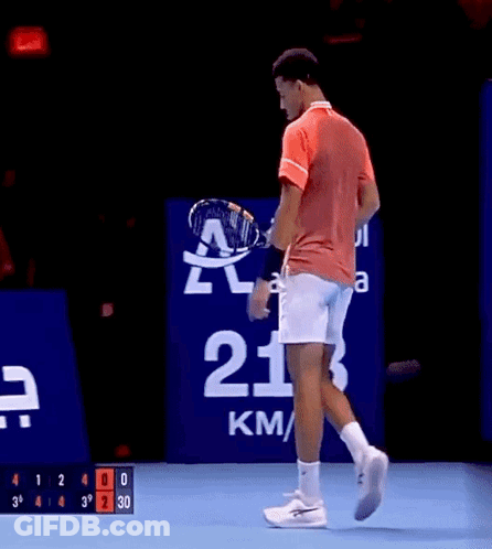 A Man In A Red Shirt And White Shorts Is Holding A Tennis Racquet GIF