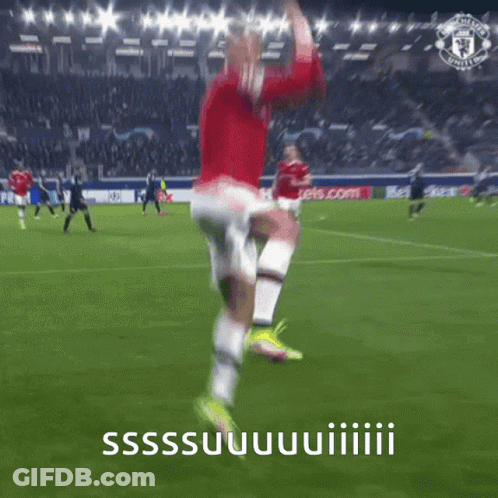 A Man In A Red Shirt And White Shorts Is Jumping In The Air On A Soccer Field GIF