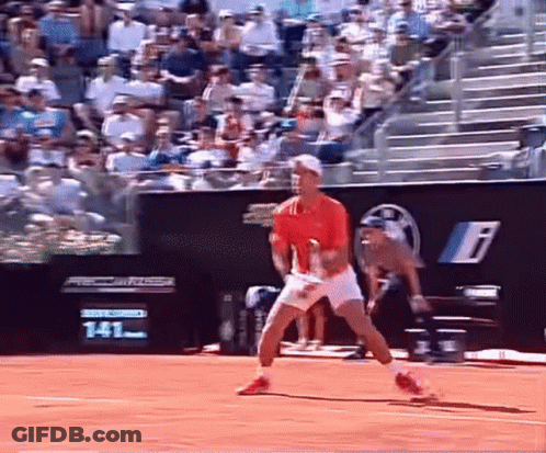 A Man In A Red Shirt And White Shorts Is Playing Tennis On A Court GIF