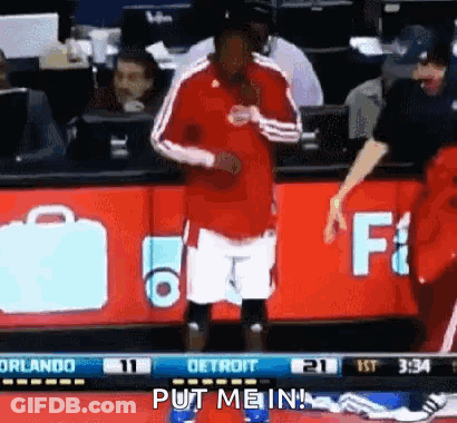 A Man In A Red Shirt And White Shorts Is Standing On A Basketball Court . GIF