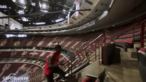 A Man In A Red Shirt Climbs The Stairs Of A Stadium GIF