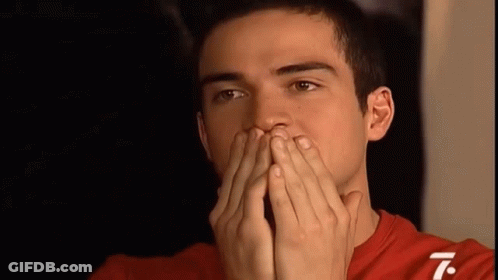 A Man In A Red Shirt Covering His Mouth With His Hands GIF