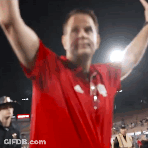 A Man In A Red Shirt Has His Arms Outstretched In The Air GIF