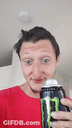A Man In A Red Shirt Holds A Can Of Monster Energy Drink GIF