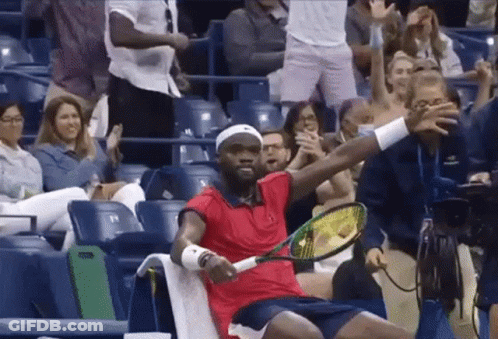 A Man In A Red Shirt Holds A Tennis Racquet In Front Of A Crowd GIF
