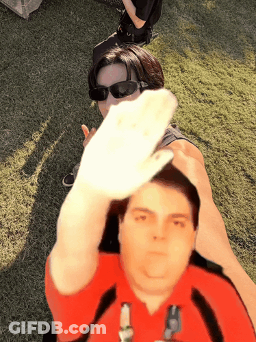 Man In Red Shirt Holding Hand In Front Of Woman GIF