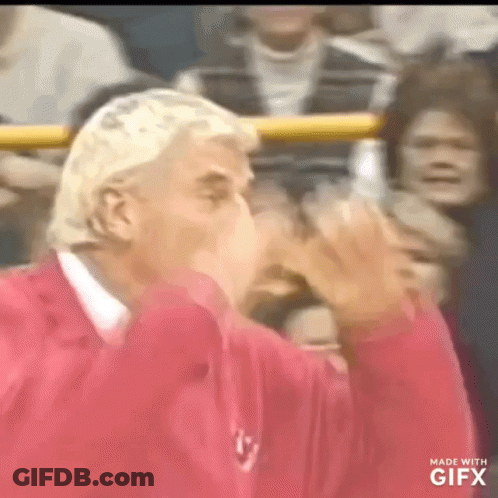A Man In A Red Shirt Is Blowing A Kiss GIF