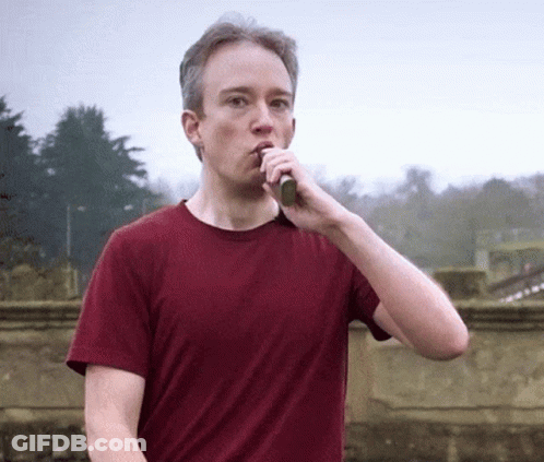 A Man In A Red Shirt Is Brushing His Teeth Outdoors GIF