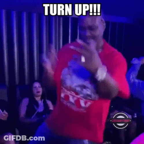 A Man In A Red Shirt Is Dancing In A Dark Room With A Caption That Says Turn Up ! GIF