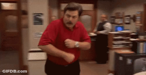 A Man In A Red Shirt Is Dancing In A Room In An Office . GIF