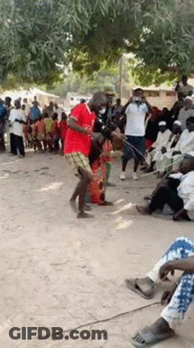 A Man In A Red Shirt Is Dancing In Front Of A Crowd . GIF