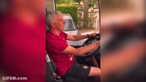 A Man In A Red Shirt Is Driving A White Car GIF