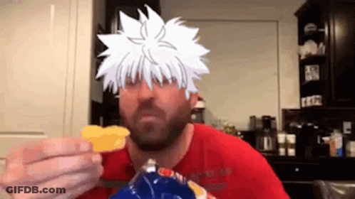 A Man In A Red Shirt Is Eating Chips With A Cartoon Character On His Face . GIF