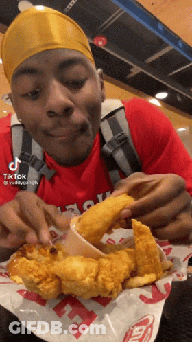 A Man In A Red Shirt Is Eating Fried Chicken And French Fries At A Fast Food Restaurant GIF