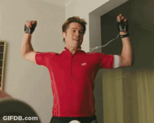 A Man In A Red Shirt Is Flexing His Arm GIF
