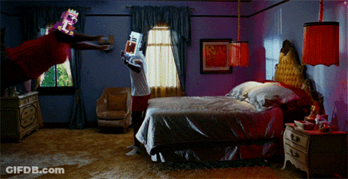 A Man In A Red Shirt Is Flying Through The Air While Holding A Game Controller In A Bedroom GIF