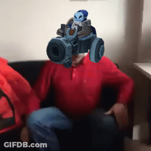 A Man In A Red Shirt Is Holding A Gun In Front Of His Head GIF