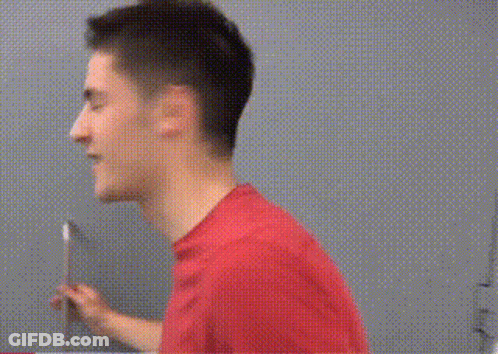 A Man In A Red Shirt Is Holding A Knife And Looking At The Camera GIF