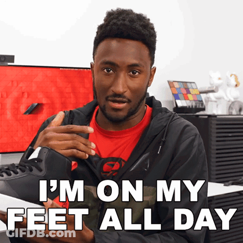 A Man In A Red Shirt Is Holding A Pair Of Shoes And Says I 'M On My Feet All Day GIF