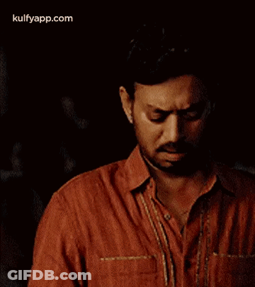 A Man In A Red Shirt Is Holding A Piece Of Paper . GIF