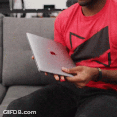 A Man In A Red Shirt Is Holding A Silver Apple Laptop GIF