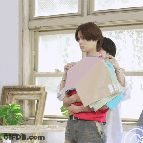 A Man In A Red Shirt Is Holding A Stack Of Paper GIF