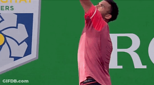 A Man In A Red Shirt Is Holding A Tennis Racquet In Front Of A Red Bull Logo GIF