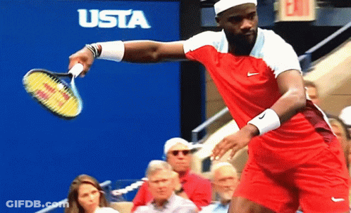 A Man In A Red Shirt Is Holding A Tennis Racquet In Front Of A Sign That Says Usta GIF