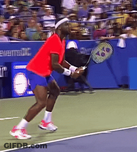 A Man In A Red Shirt Is Holding A Tennis Racquet On A Court GIF