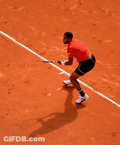 A Man In A Red Shirt Is Holding A Tennis Racquet On A Tennis Court GIF