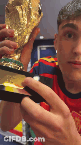 A Man In A Red Shirt Is Holding A Trophy That Says ' Fifa World Cup ' On It GIF