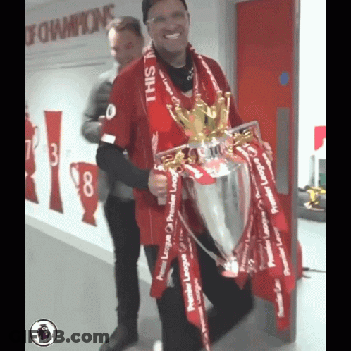 A Man In A Red Shirt Is Holding A Trophy That Says Premier League On It GIF