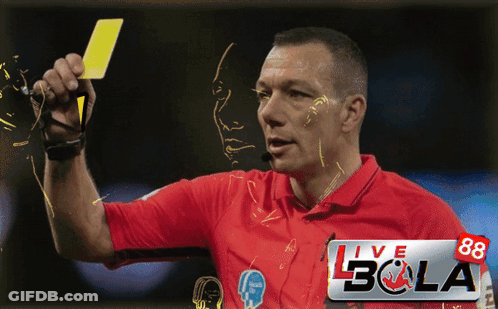 A Man In A Red Shirt Is Holding A Yellow Card In Front Of A Banner That Says Live Bola GIF