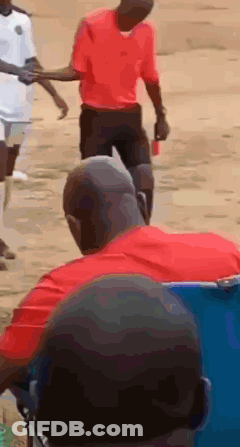 A Man In A Red Shirt Is Holding Another Man 'S Hand While Walking GIF