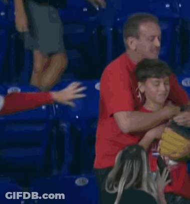 A Man In A Red Shirt Is Hugging A Young Boy GIF