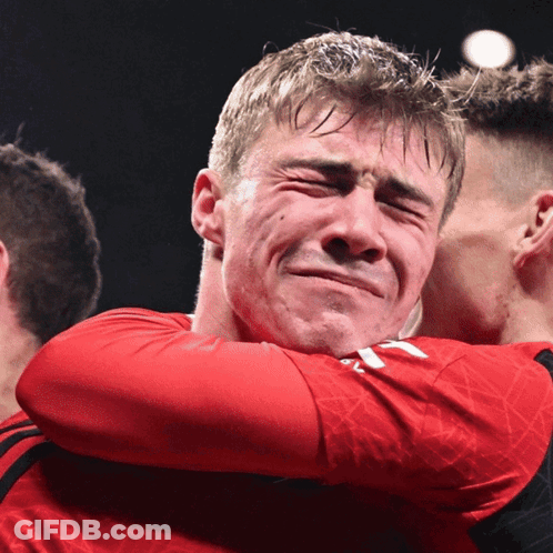 A Man In A Red Shirt Is Hugging Another Man Who Is Crying GIF