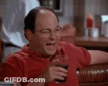 A Man In A Red Shirt Is Laughing While Holding A Glass Of Coke . GIF