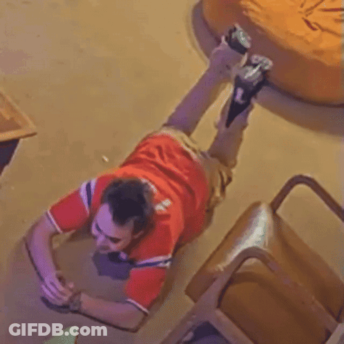 A Man In A Red Shirt Is Laying Down On The Floor GIF