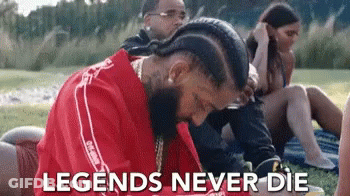 A Man In A Red Shirt Is Laying On The Grass With The Words `` Legends Never Die '' Written Above Him . GIF