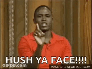 A Man In A Red Shirt Is Making A Funny Face And Pointing At The Camera . GIF