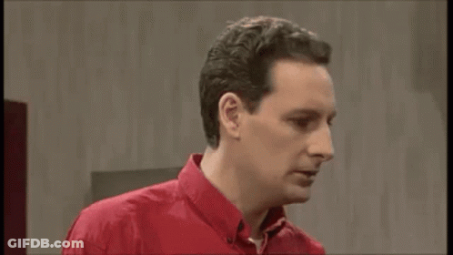 A Man In A Red Shirt Is Making A Funny Face While Looking At The Camera . GIF