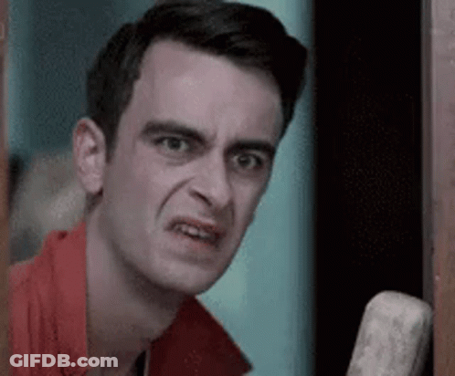 A Man In A Red Shirt Is Making A Funny Face While Standing In A Doorway . GIF