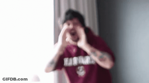 A Man In A Red Shirt Is Making A Heart Shape With His Hands In Front Of His Face . GIF