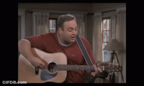 A Man In A Red Shirt Is Playing A Guitar GIF