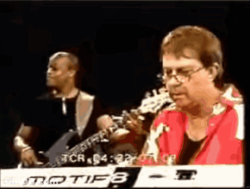 A Man In A Red Shirt Is Playing A Keyboard With Motif8 Written On It GIF