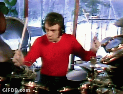A Man In A Red Shirt Is Playing Drums . GIF