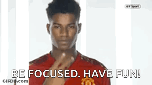 A Man In A Red Shirt Is Pointing At The Camera With The Words Be Focused Have Fun Below Him GIF