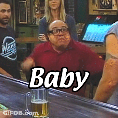 A Man In A Red Shirt Is Sitting At A Bar With A Glass Of Beer In Front Of Him And The Word Baby Written On It GIF