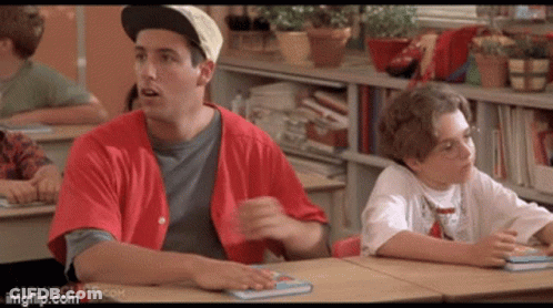 A Man In A Red Shirt Is Sitting At A Desk Next To A Boy In A White Shirt GIF